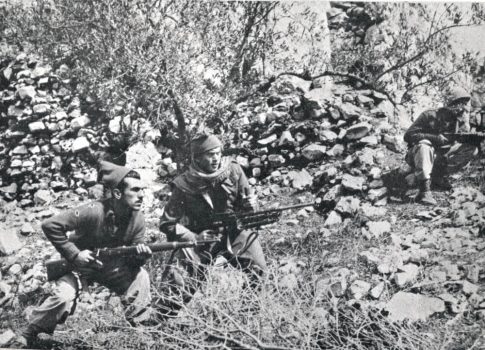 Palmach fighters crouch between stone terraces by San Simon Monastery, waiting for the commander to advance