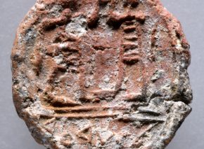 The tiny clay disc shows the imprint of a seal carved with two male figures above the inscription "to the City governor"