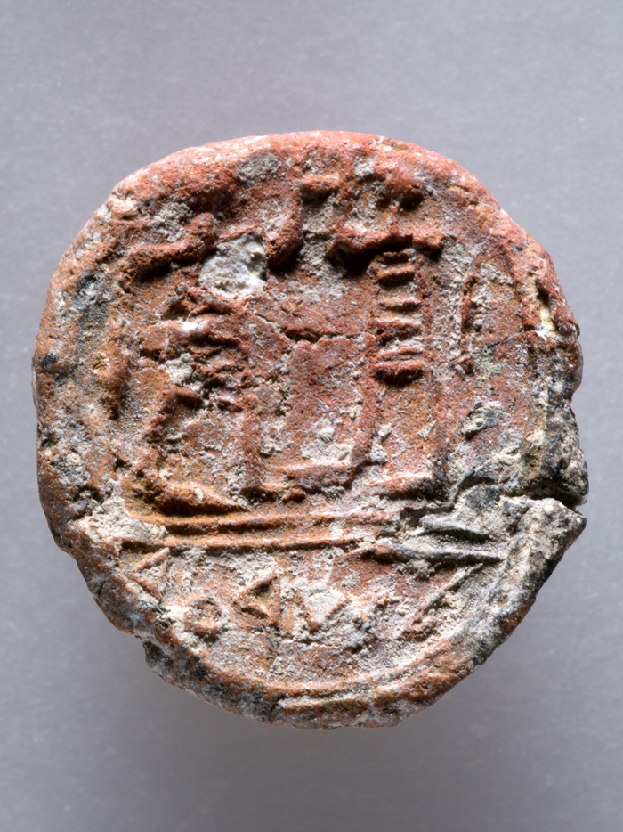 The tiny clay disc shows the imprint of a seal carved with two male figures above the inscription "to the City governor"