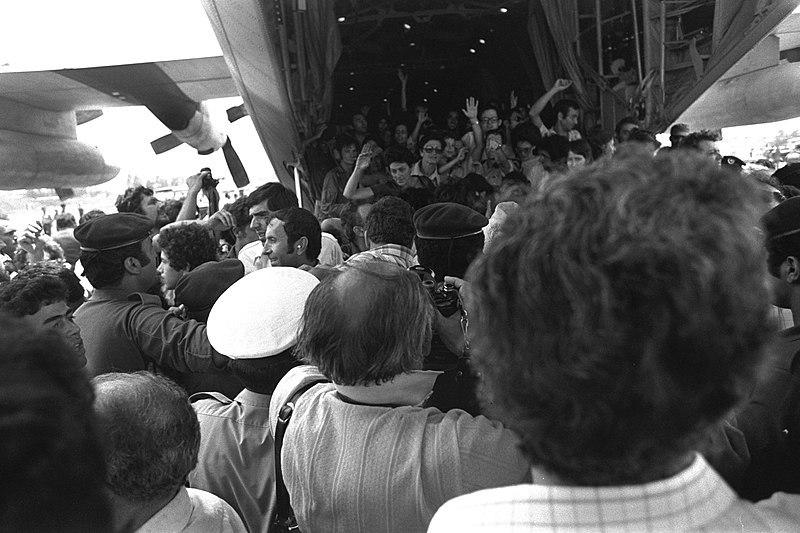 Rescued Air France passengers wave to the waiting crowd while leaving the belly of the Hercules plane at Ben-Gurion Airport