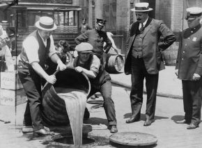 A policeman supervises the disposal of confiscated liquor on the streets of New York, 1921